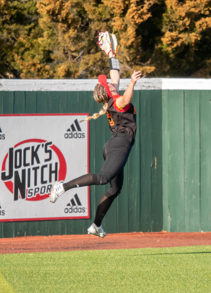 PSU freshman left fielder Heather Arnett leaps to snag a hit away from a Rockhurst batter on March 5, 2023, at the Pitt State Softball Complex.